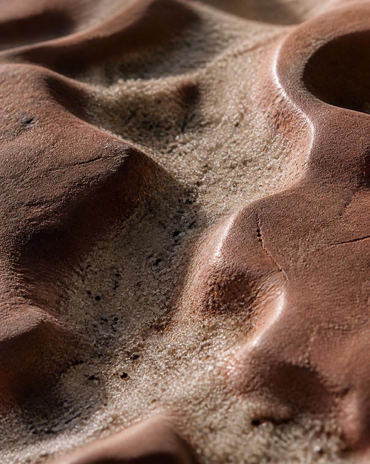 Macro close-up of raw matte quartz sand valleys against hand-polished satin-waxed terracotta ridge plateaus